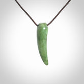 This is a lovely New Zealand Jade, pounamu niho drop pendant. Hand carved for us by Ric Moor. It is bound with an adjustable brown coloured cord which is length adjustable. Free worldwide shipping.